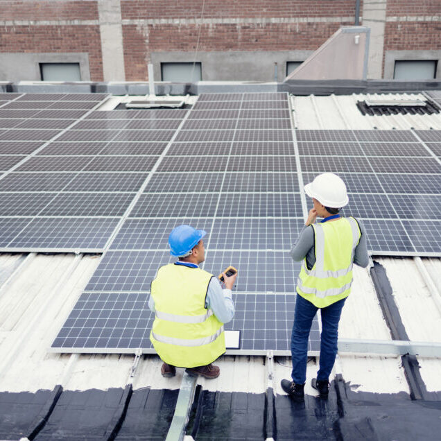 two workers are standing on the roof of a building